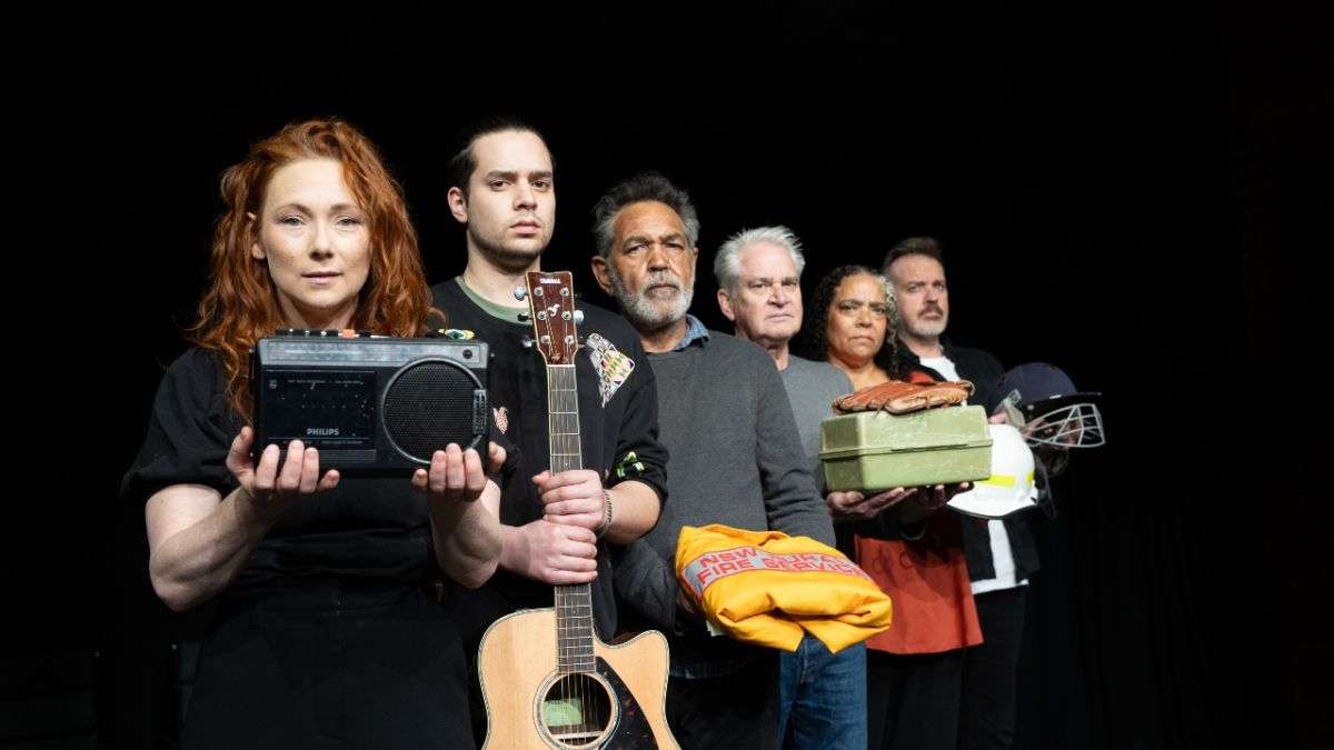 Six cast members of play standing in a line, each holding a different prop from the play